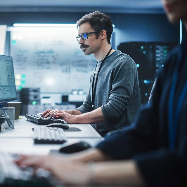 Portrait of a thoughtful engineer working on a desktop computer in a technological office environment.