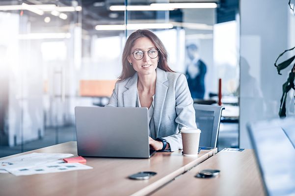 A young woman looks up from her laptop.