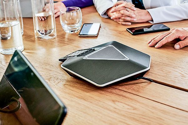 Several smartphones lie around a telephone spider on a meeting table.