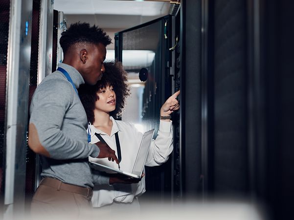 Two people inspect a Telekom server cabinet.