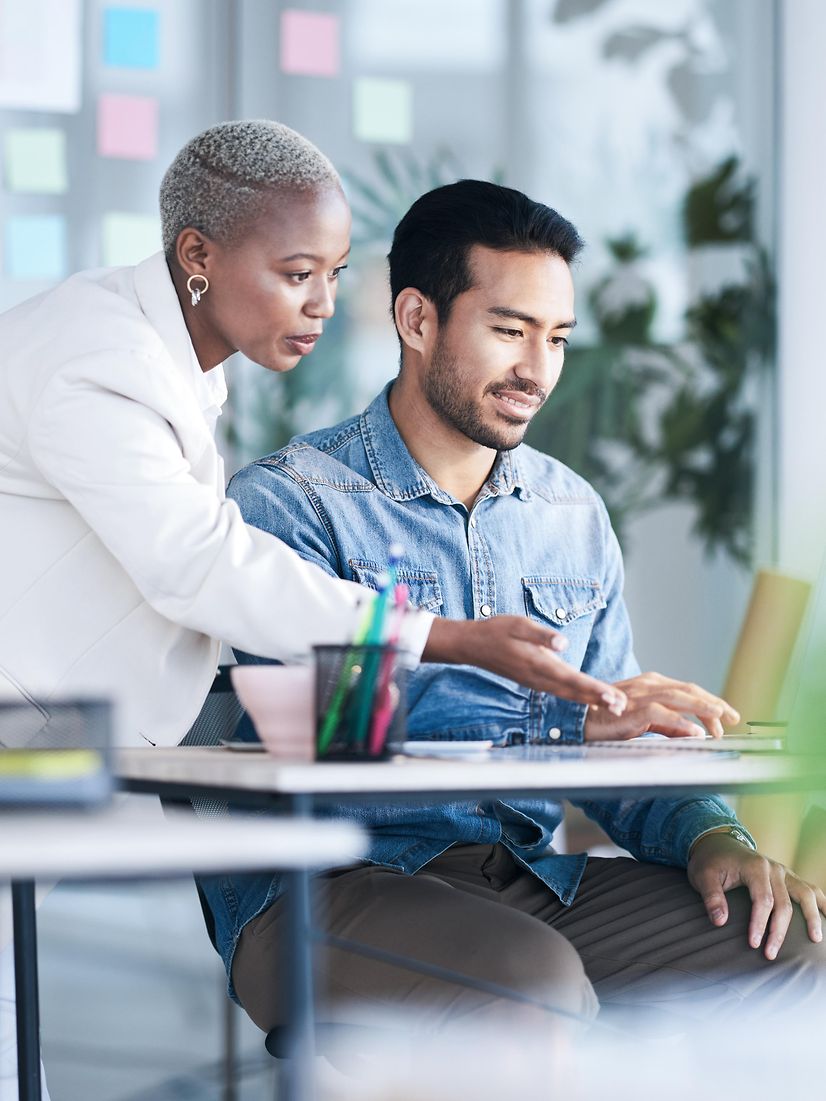 Two people, a woman and a man, are talking to each other at a desk.
