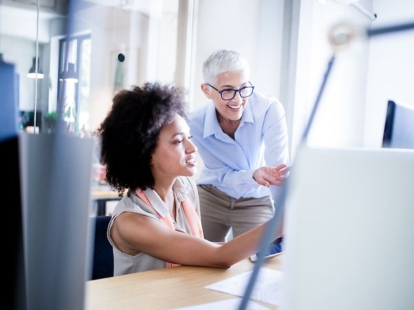 Two women discussing a project in front of a computer screen