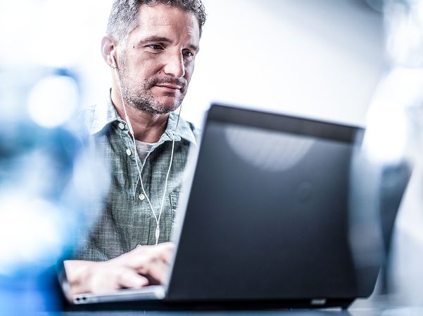 Man wearing headphones working on a laptop with Microsoft Copilot