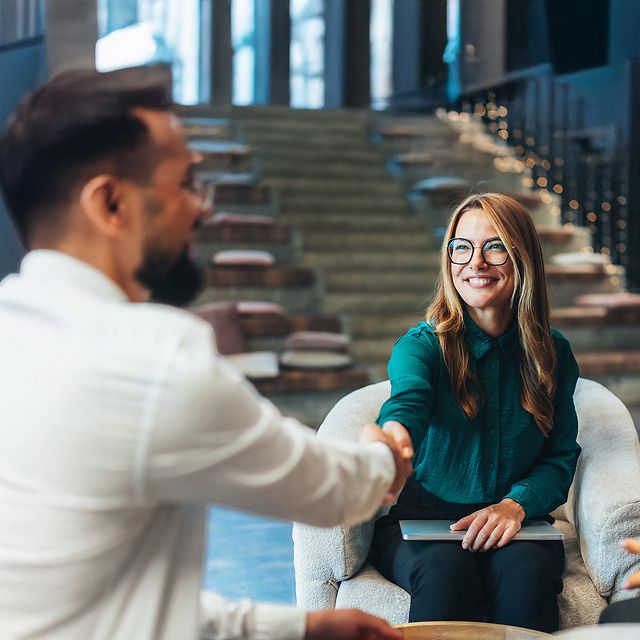 A woman and a man shake hands at the beginning of a consultation meeting about Swyx X.