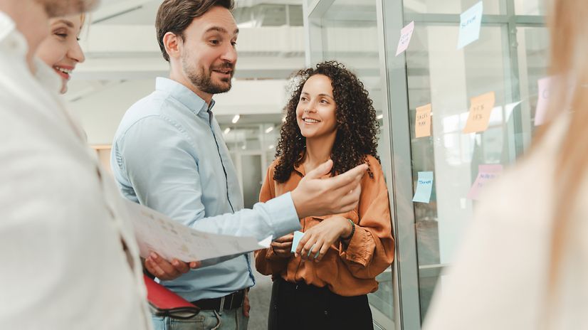 Several people are working together in an open-plan office and talking about Hubdrive.
