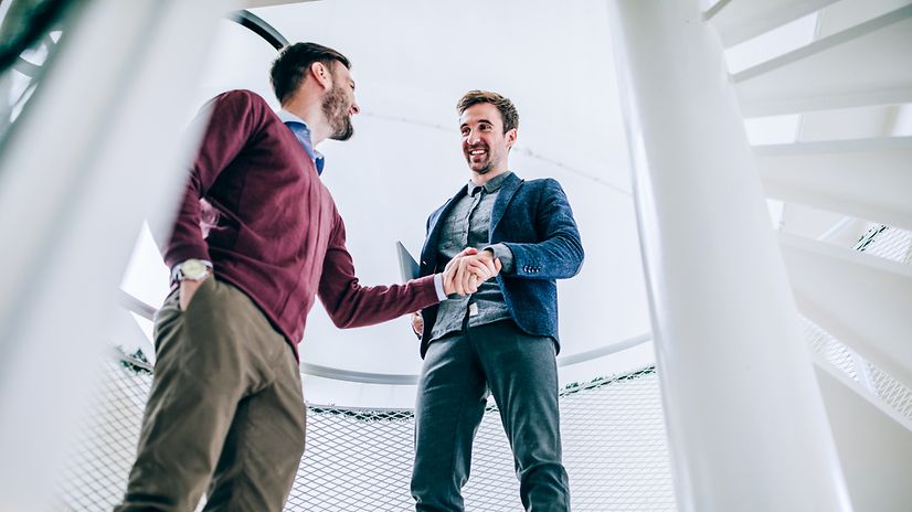 An employee shakes hands with a customer, both smile.