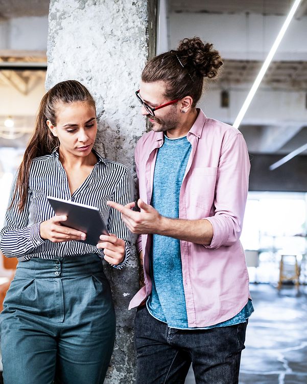 Two people with tablets discuss Telekom's SAP solutions for small and medium-sized businesses in a modern office.