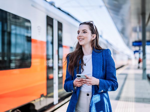 A woman stands at the railway platform and reads a message that was sent via mass text messaging.