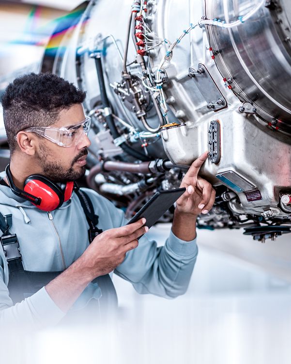 Aircraft maintenance mechanic checking data in front of the jet engine