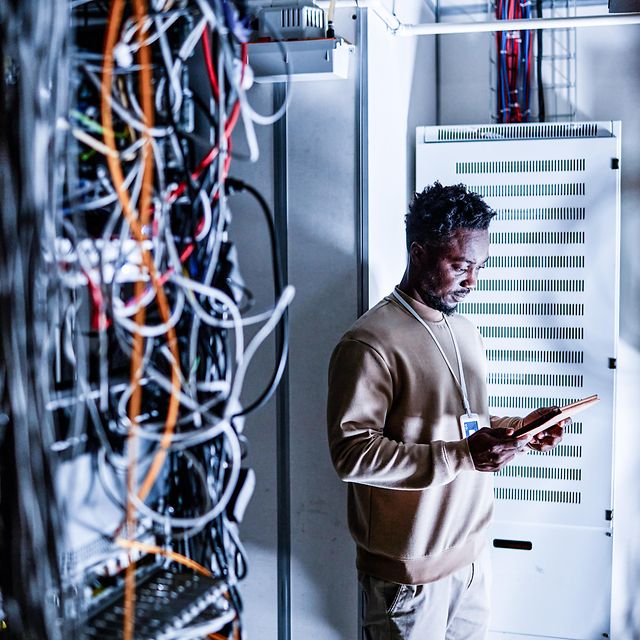 A technician stands in front of a Telekom server cabinet.