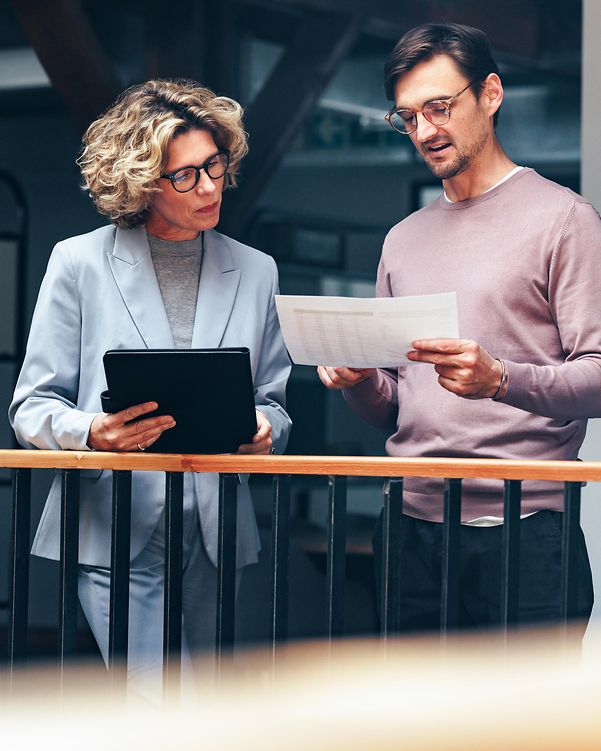 Business people reading a document together. Two experts analysing a cloud infrastructure proposal in an office.