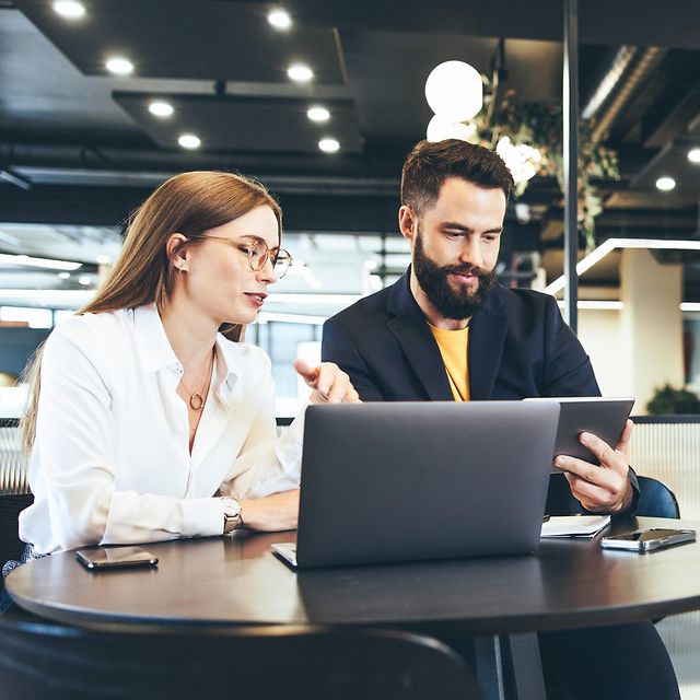 Two people working remotely in a public place with Managed Workplace