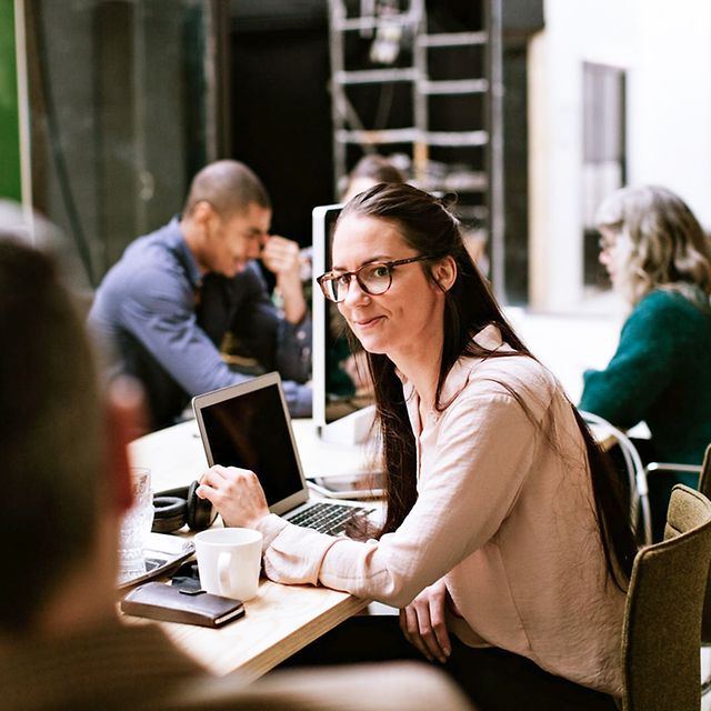 A woman in an open-plan office chats with a colleague about managed IT services.