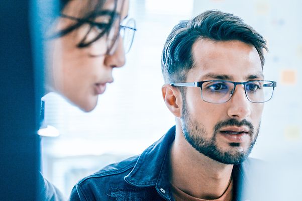 Two employees look at the screen and read about Jamf Mobile Security & Data Management.
