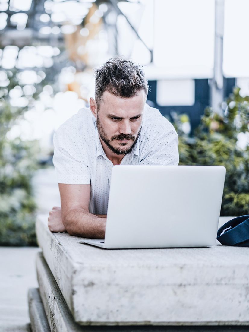 Man sits outside and works with a stable mobile connection thanks to Mobile Optimisation Pro.