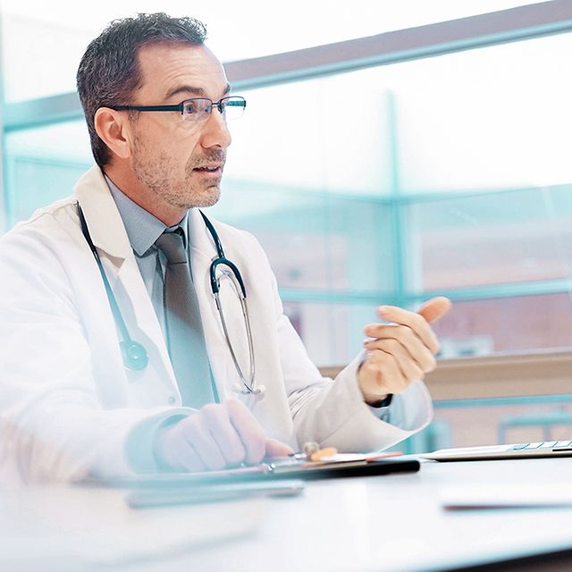 Doctor sitting in front of a laptop in his practice and using Telekom's telematics solution