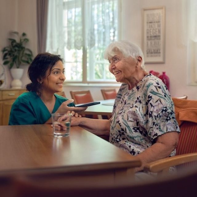 Caregiver simultaneously translates for an elderly woman using her smartphone.