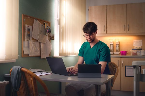 Caregiver documents his work on his laptop in the staff room.