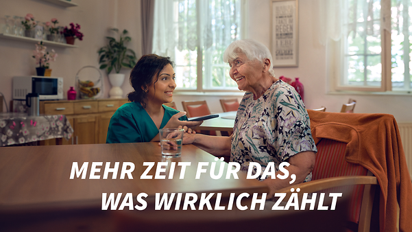 Carer and elderly lady communicate via a translation app on a smartphone