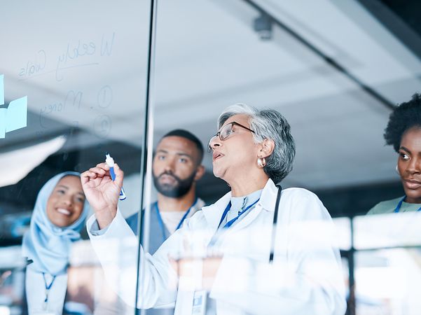 Several doctors stand in front of a planning board in a hospital and use the telematics solution.