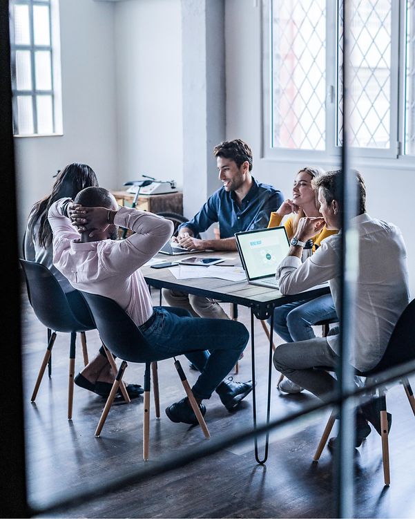 A team sits at a conference table with a MacBook on it.