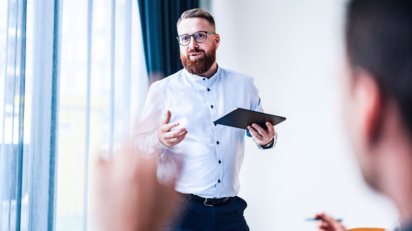 Man standing in front of an audience with a tablet