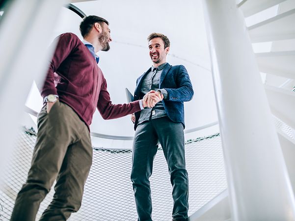 Two men seal an agreement with a handshake.