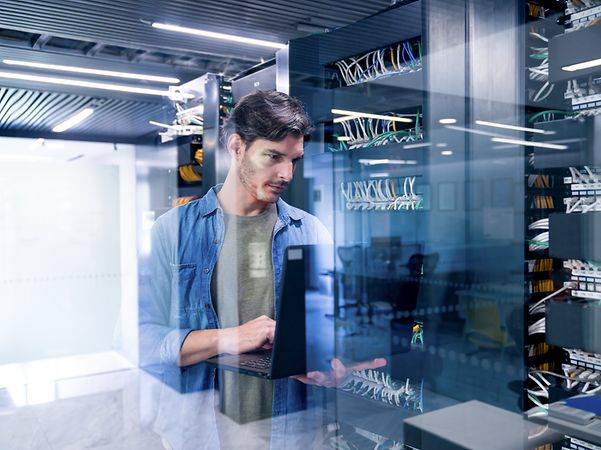 An IT expert sets up web hosting for a business website and domain using his laptop.