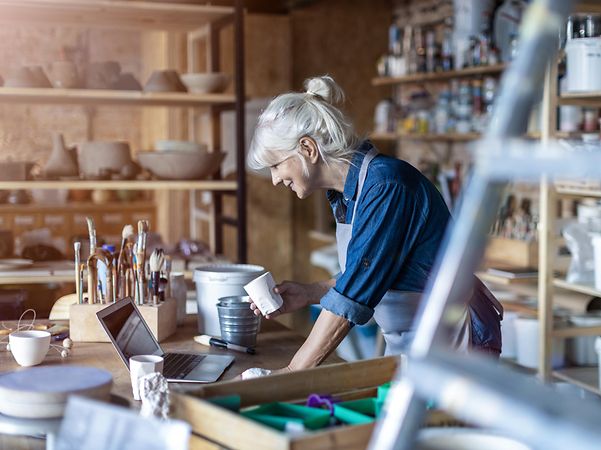A craftswoman looks at her workshop's website on her laptop and is delighted with her e-commerce successes.