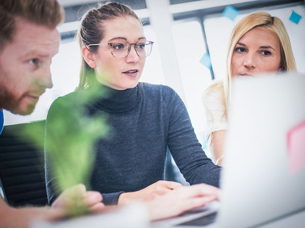 Three people are looking intently at a screen.