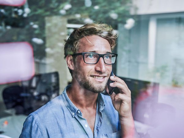 A man is on the phone and looking out of the window.