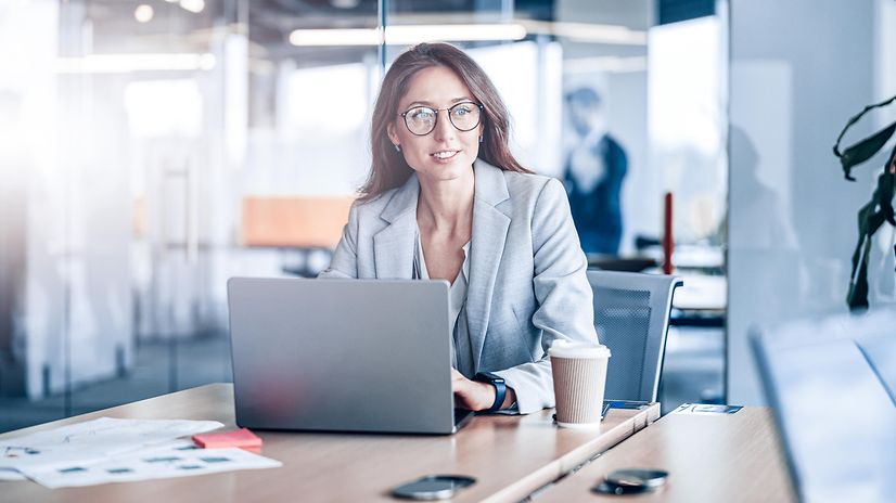 Smiling businesswoman with glasses working on a laptop in a modern office in a company