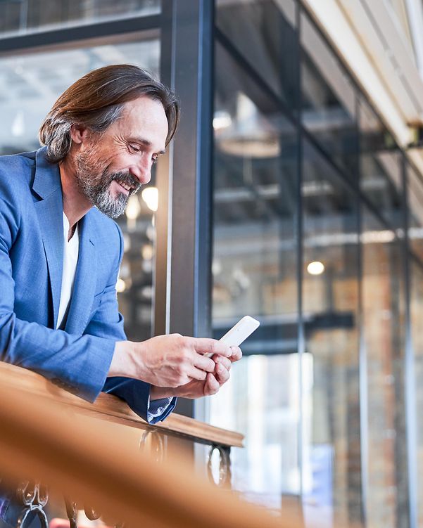A smiling businessman is delighted with his company's dedicated internet access as he looks at his mobile phone.