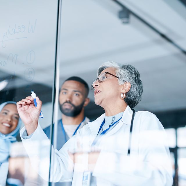Several doctors stand in front of a planning board in a hospital and use the telematics solution.