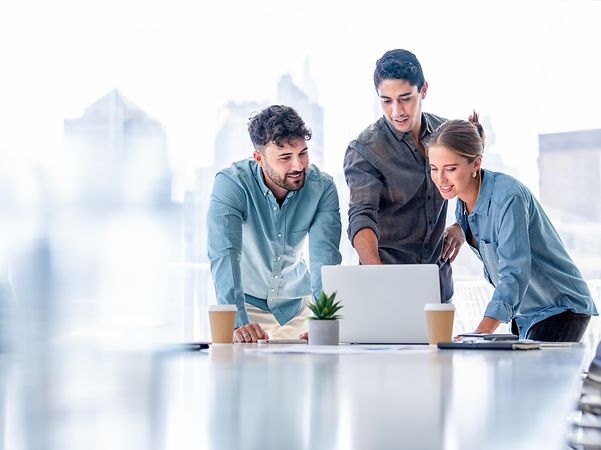 Business team standing in a meeting room and working on a laptop computer
