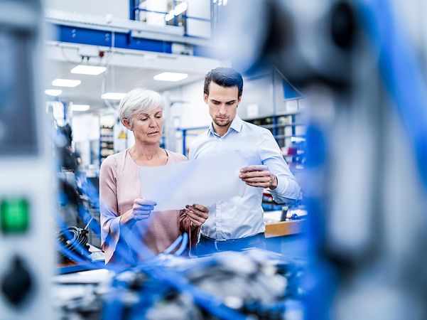 Businesswomen and businessmen look at the plan in a factory