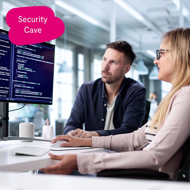 Zwei Personen betrachten Quellcode auf großen Monitoren in einem modernen Büro und diskutieren darüber.
