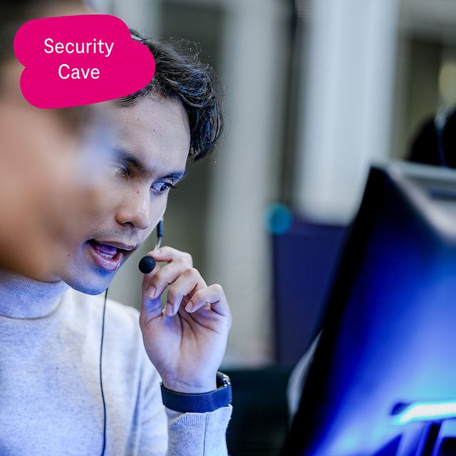 Person wearing a headset concentrates on a desktop monitor in an office environment.