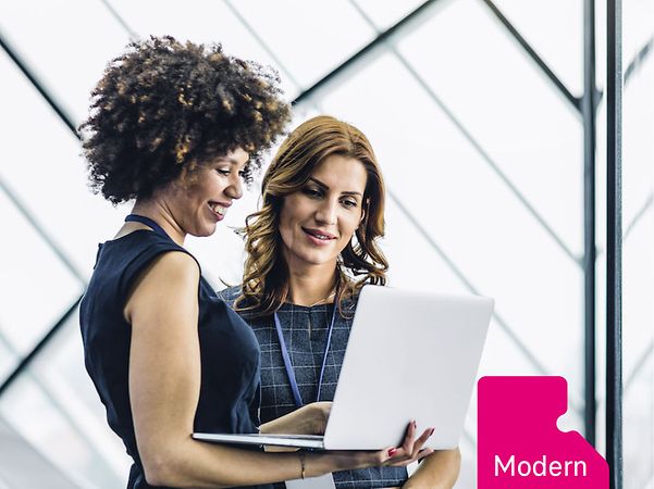 Two businesswomen look together at an open laptop, next to which is an icon labelled 'Modern Work'.