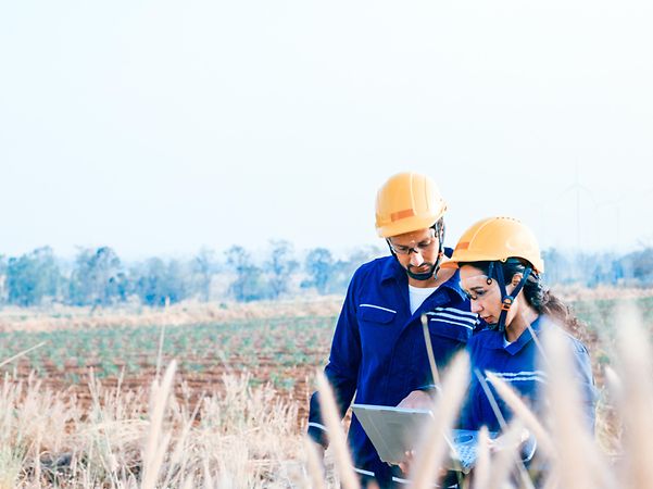 Techniker überprüfen technische Daten auf dem Laptop auf einem riesigen landwirtschaftlichen Feld
