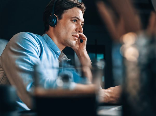 Support-Mitarbeiter mit Headset arbeitet konzentriert an einem Computer im Büro.