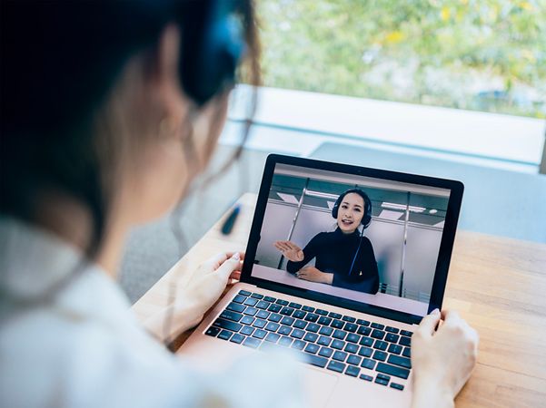 Person führt ein Video-Call mit einer Beraterin auf einem Laptop durch.