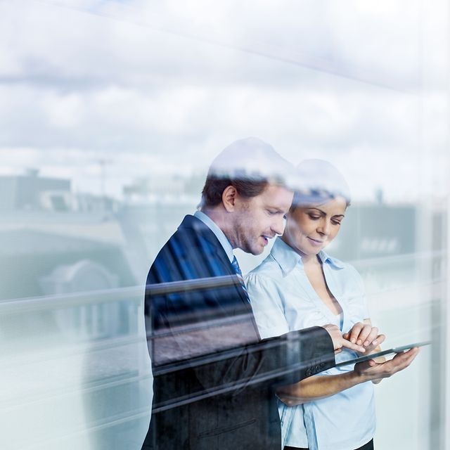 Zwei Erwachsene im Business Outfit betrachten den Telekom Festnetz Tarifberater und die Produktempfehlungen auf einem Tablet.