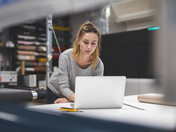 Eine Frau erstellt an ihrem Laptop die Website ihrer Firma mit dem Homepage Baukasten der Telekom.