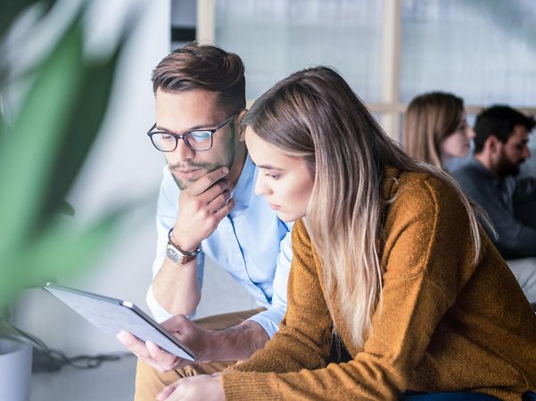 Eine Frau und ein Mann betrachten auf einem Tablet verschiedene Lösungen für das Management mobiler Endgeräte