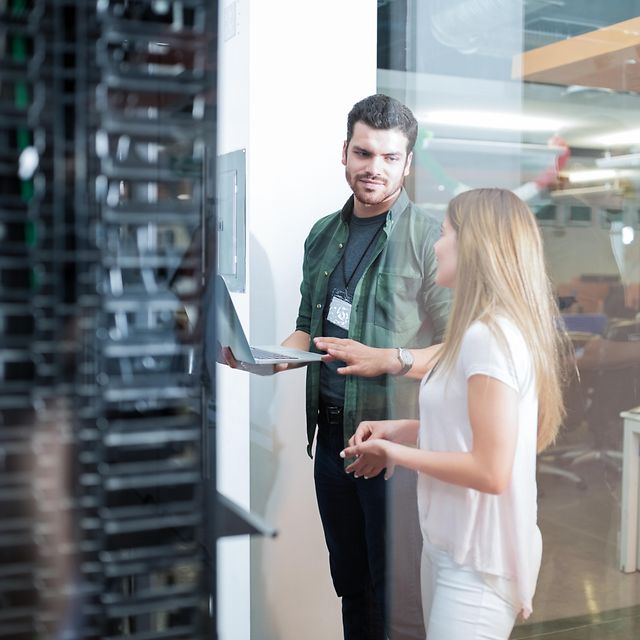 Eine Frau und ein Servicetechniker stehen vor einem Serverschrank und sprechen über Magenta Secure SD-LAN Cisco.