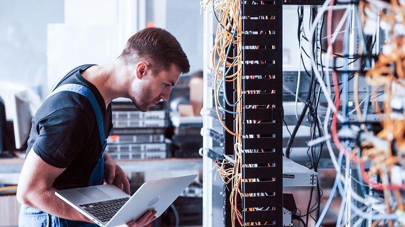 Ein Techniker mit Laptop vor einem Serverschrank für Magenta Secure SD-WAN auf Basis Fortinet