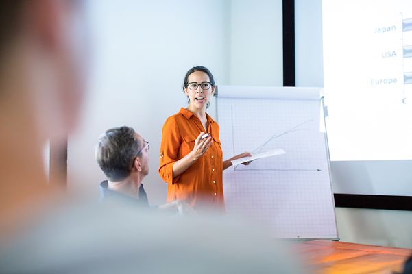 Eine weibliche Führungskraft präsentiert ihren Vorgesetzten die Personalstatistiken