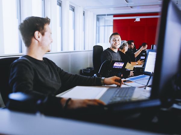 Mitarbeiter im Großraumbüro an Laptops sitzend