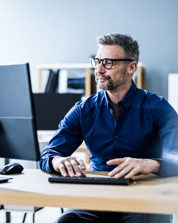 Mann mit Brille signiert mit DocuSign ein Dokument an seinem Laptop